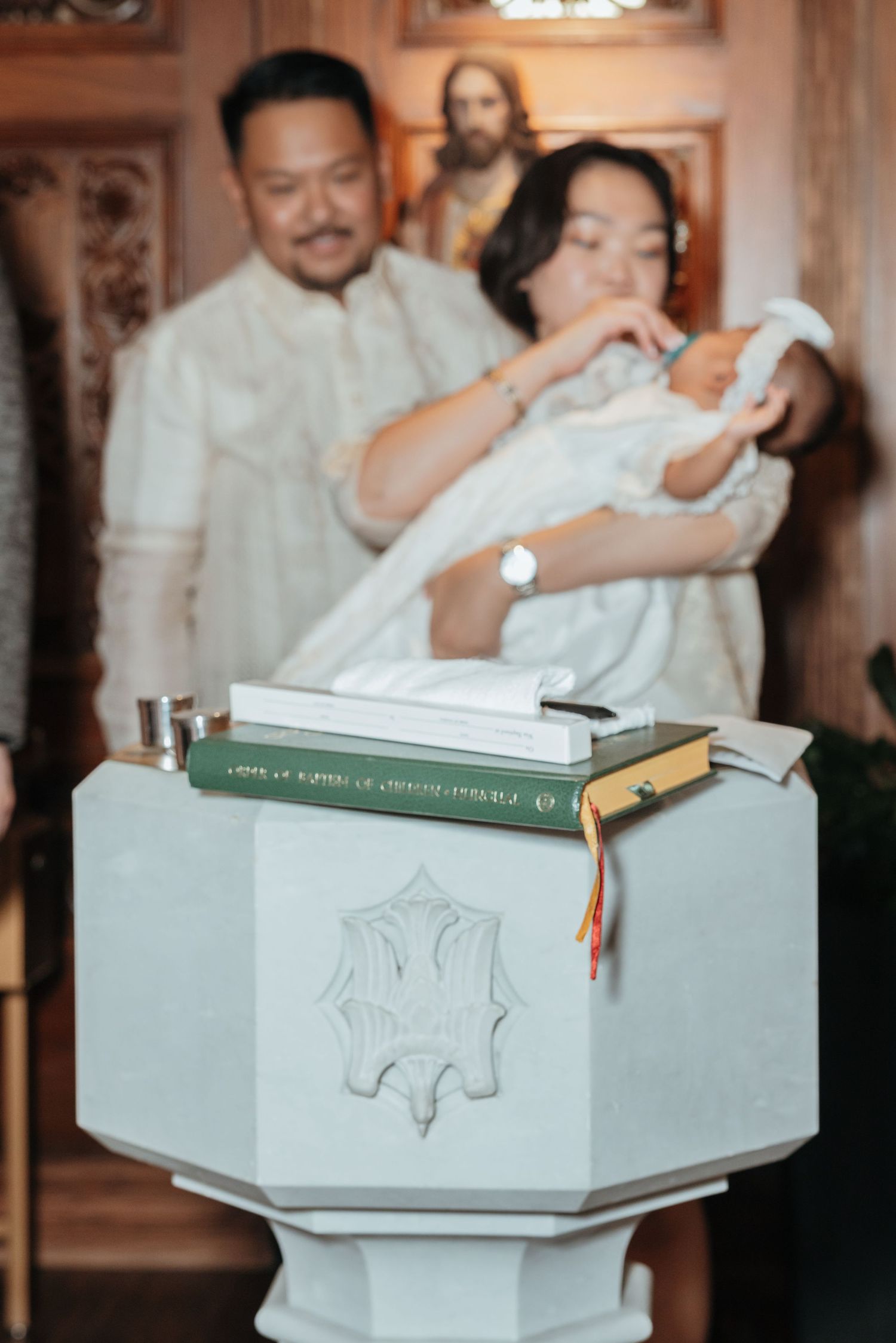A baptismal font with religious books in a Catholic church during a baby baptism ceremony.