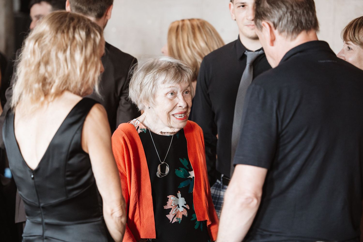 Senior woman smiling warmly while conversing at an elegant social gathering.