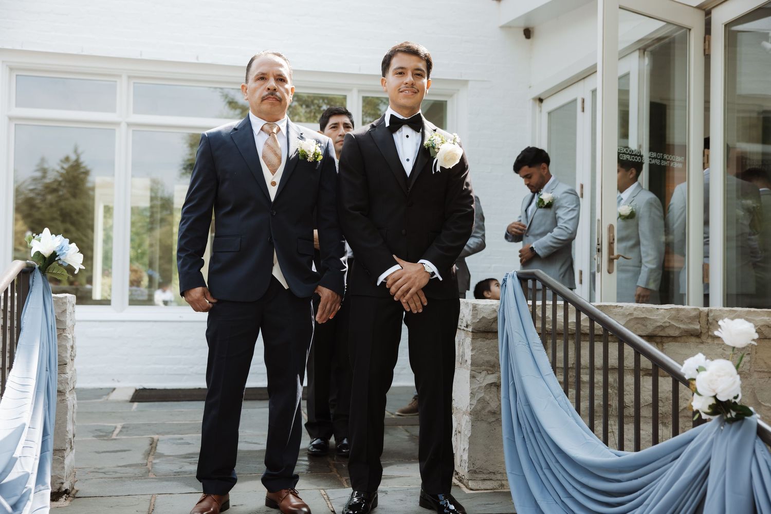 Groom and father standing outside venue before wedding ceremony.