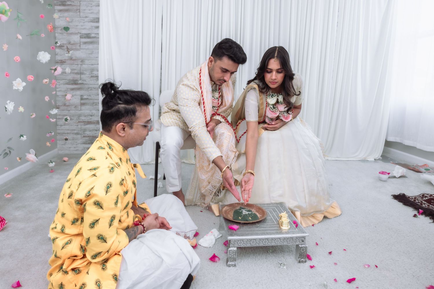 Indian bride and groom conducting sacred havan ceremony with priest officiating.