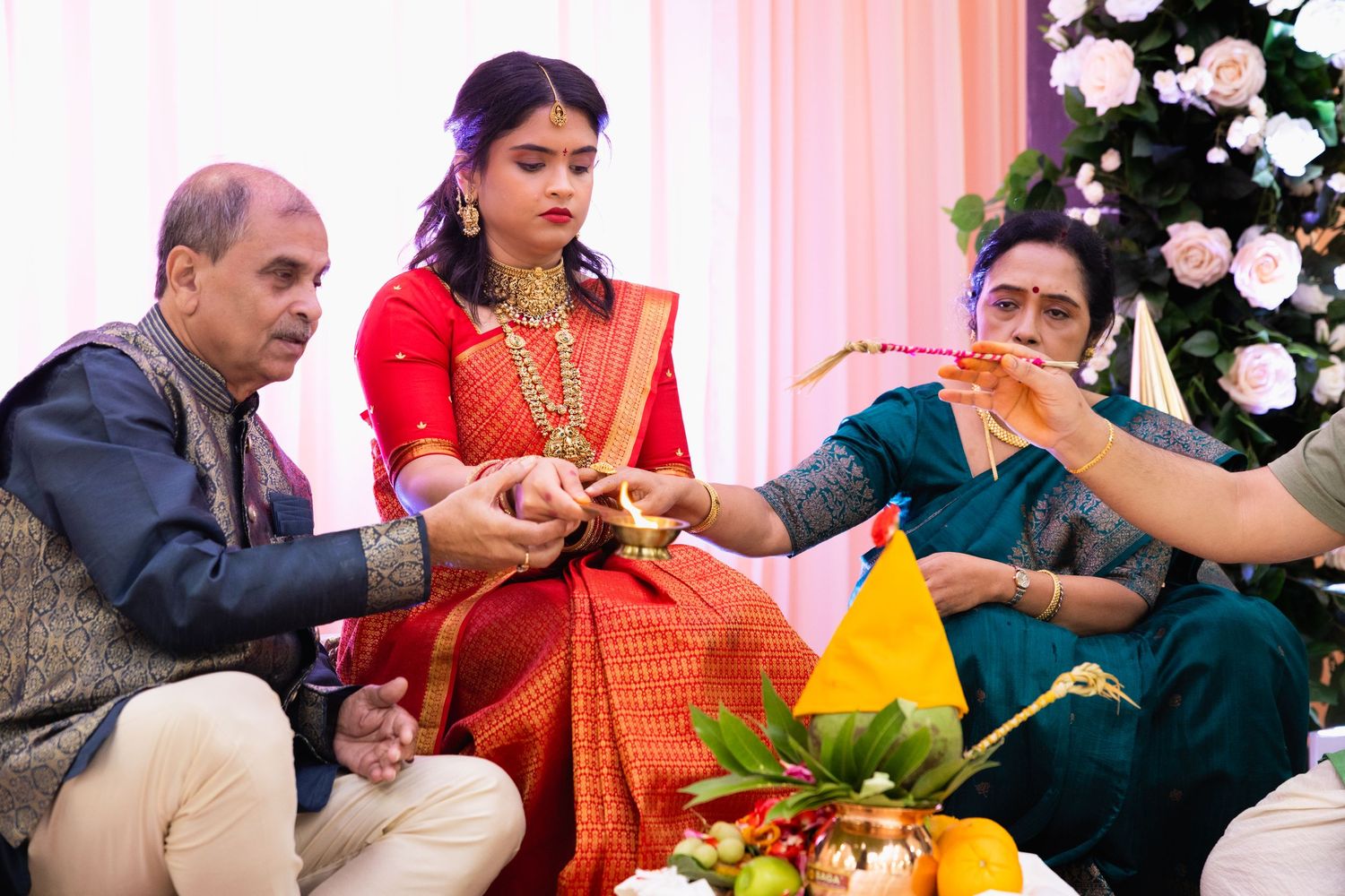 Hindu wedding ceremony with bride in red saree receiving blessings during traditional ritual with family.
