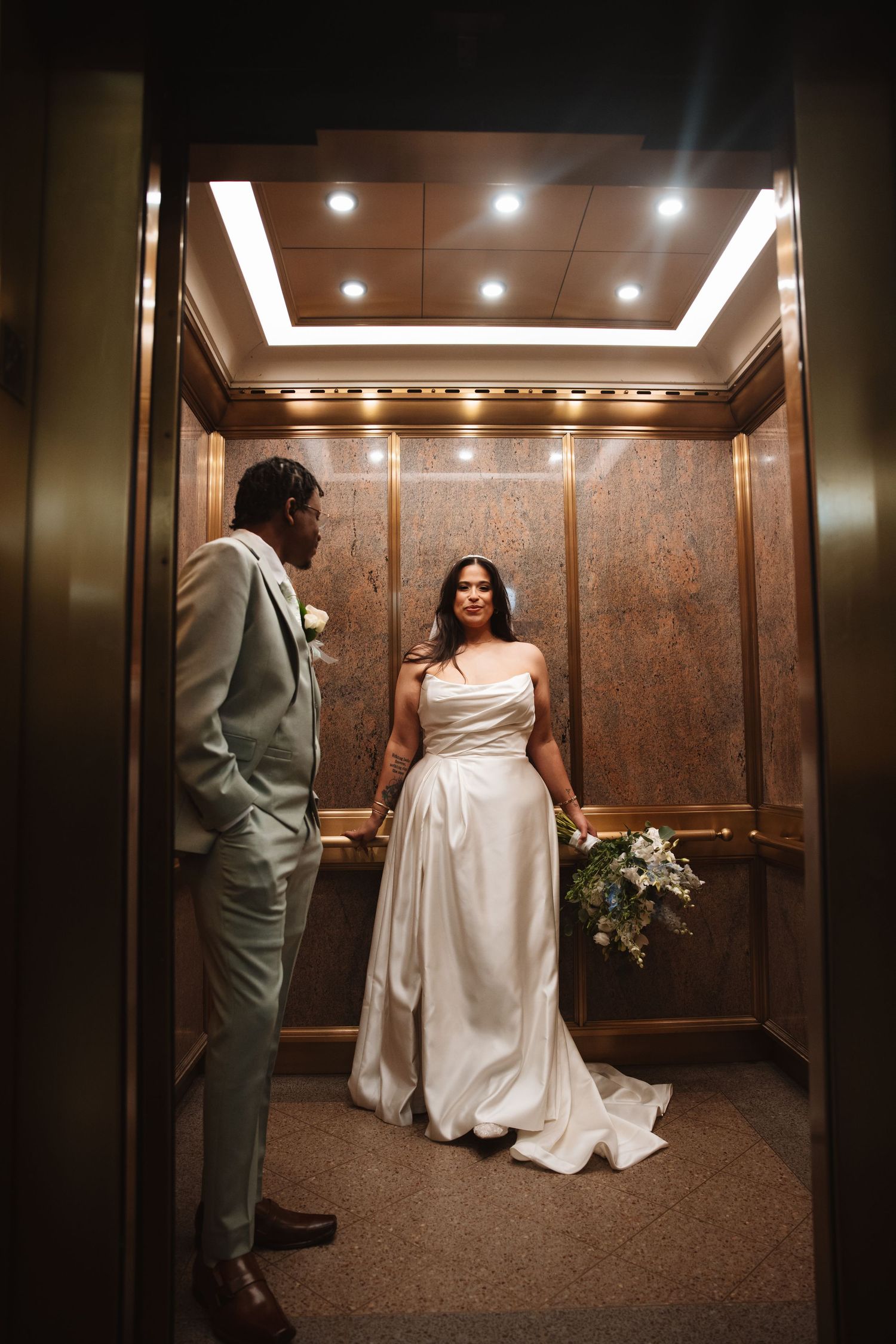 Bride and groom share a moment inside an elegant wood-paneled elevator.