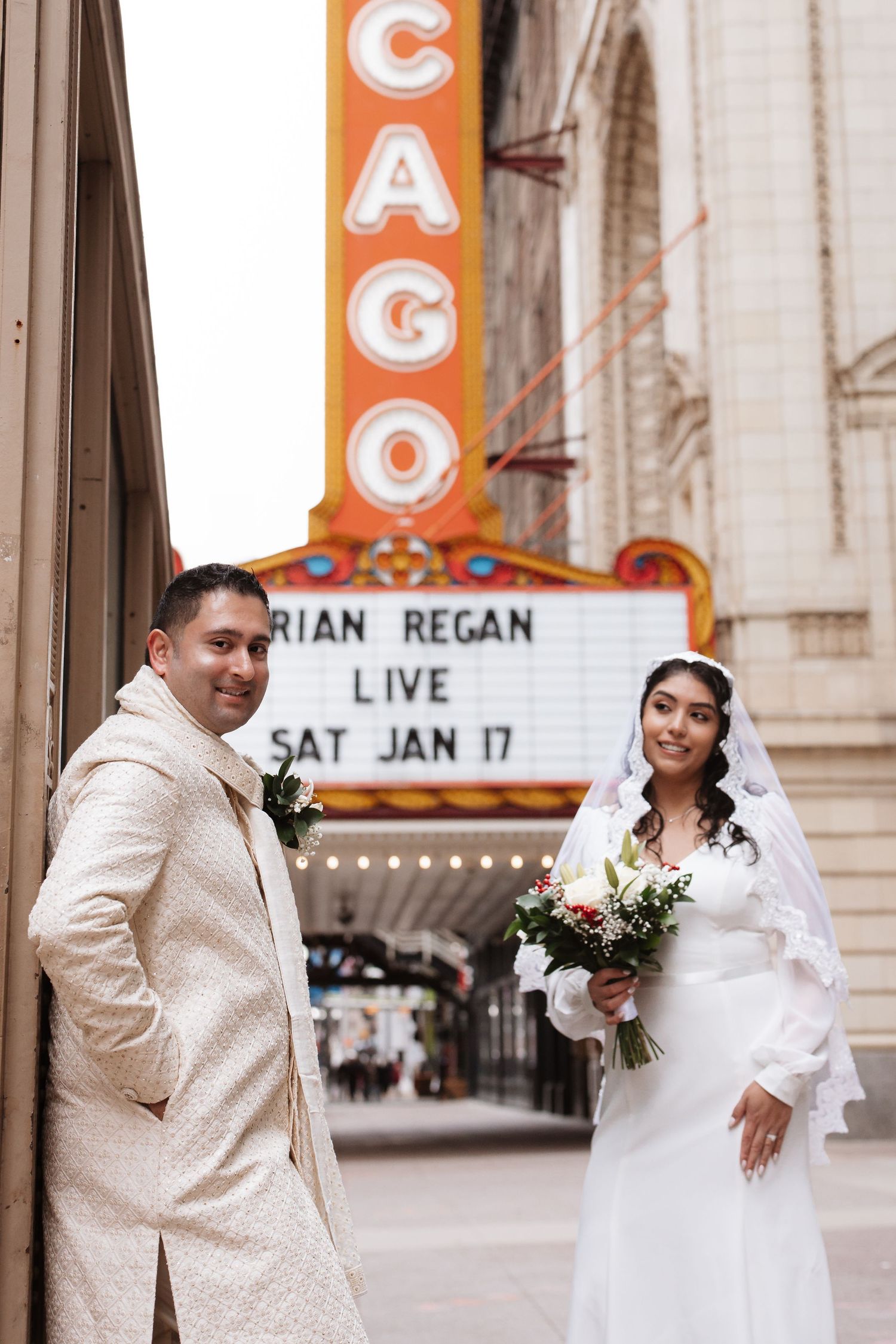 Bride and groom pose separately outside Chicago Theatre with Brian Regan Live marquee sign.