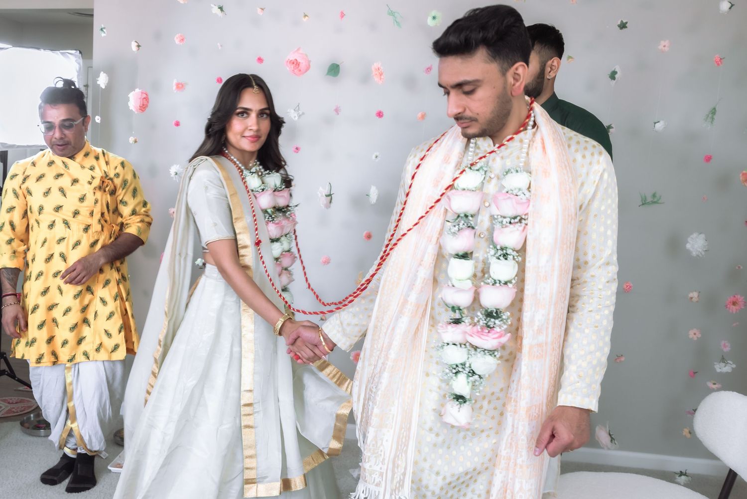 Indian bride and groom in traditional attire holding hands at wedding ceremony.