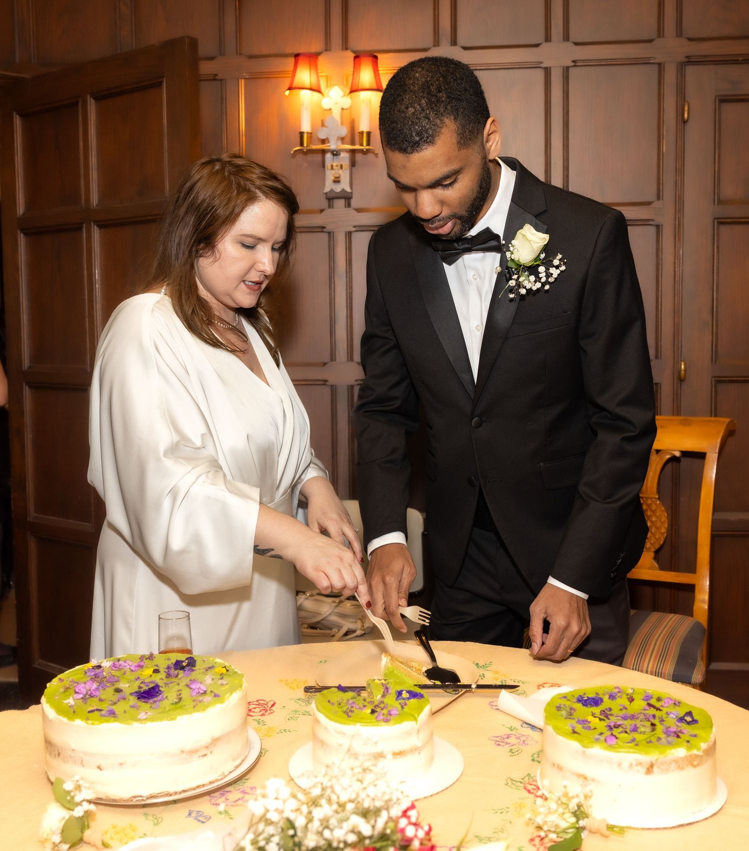 Bride and groom in tuxedo cutting decorated wedding cake at formal reception.