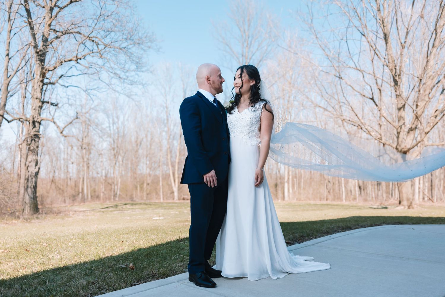 Bride and groom share a tender moment gazing at each other outdoors on wedding day.