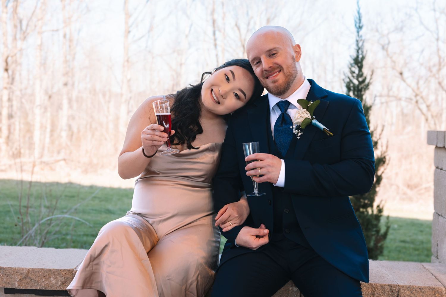 Smiling bride and groom sitting together toasting with wine at their wedding.