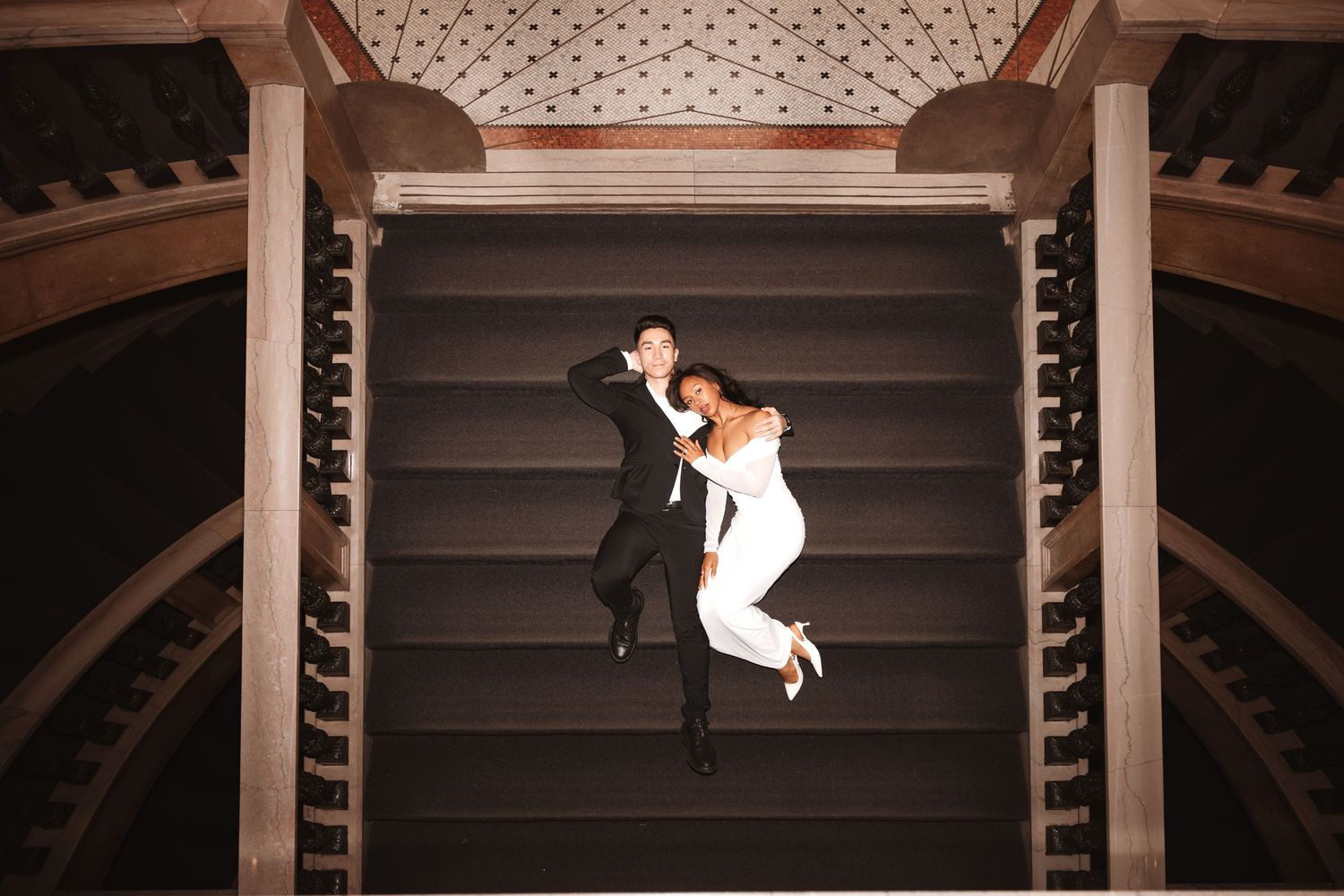 Aerial view of bride and groom embracing on grand staircase, captured from above.Chicago Wedding Photographer