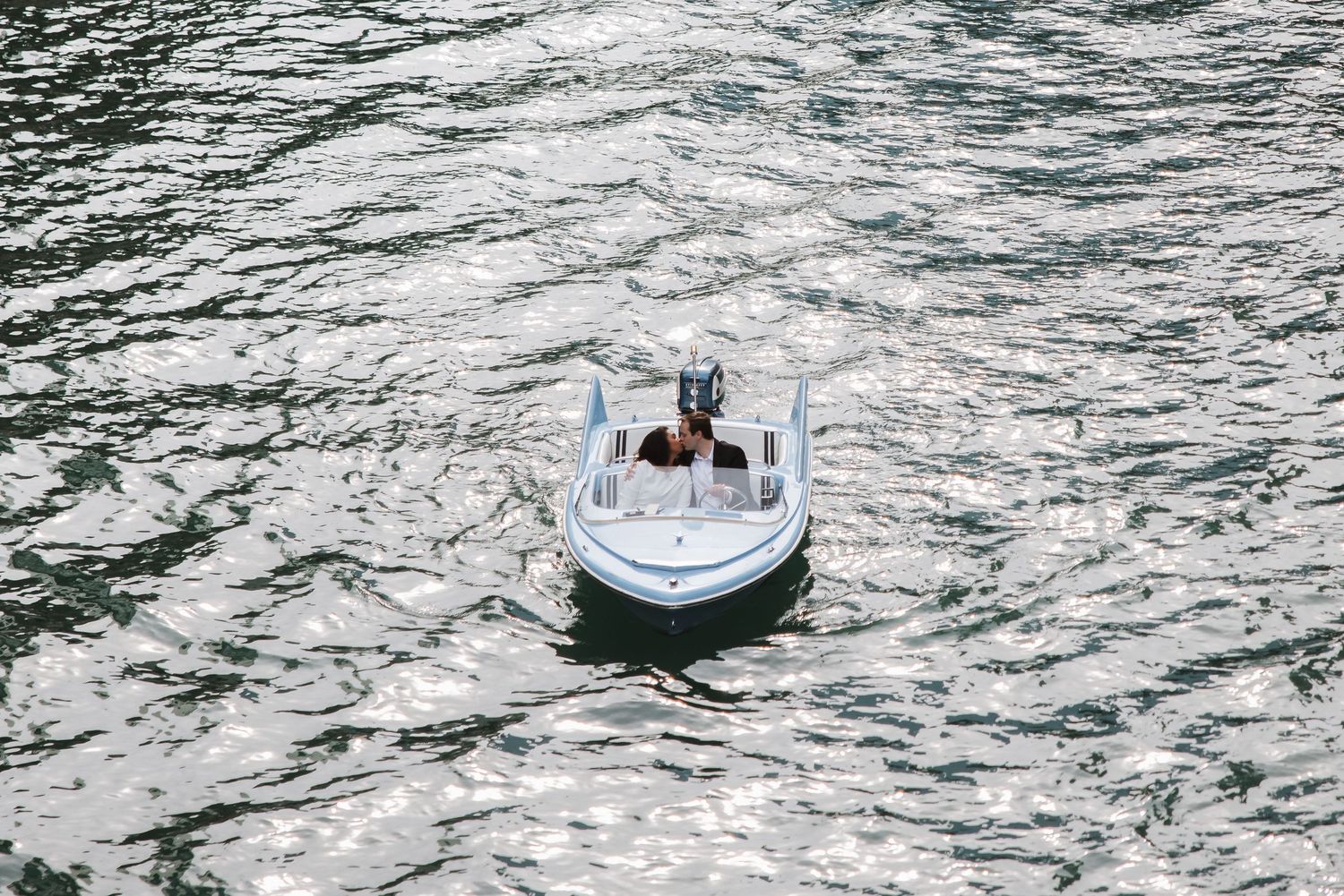 Aerial view of a small white speedboat cruising on shimmering open water.