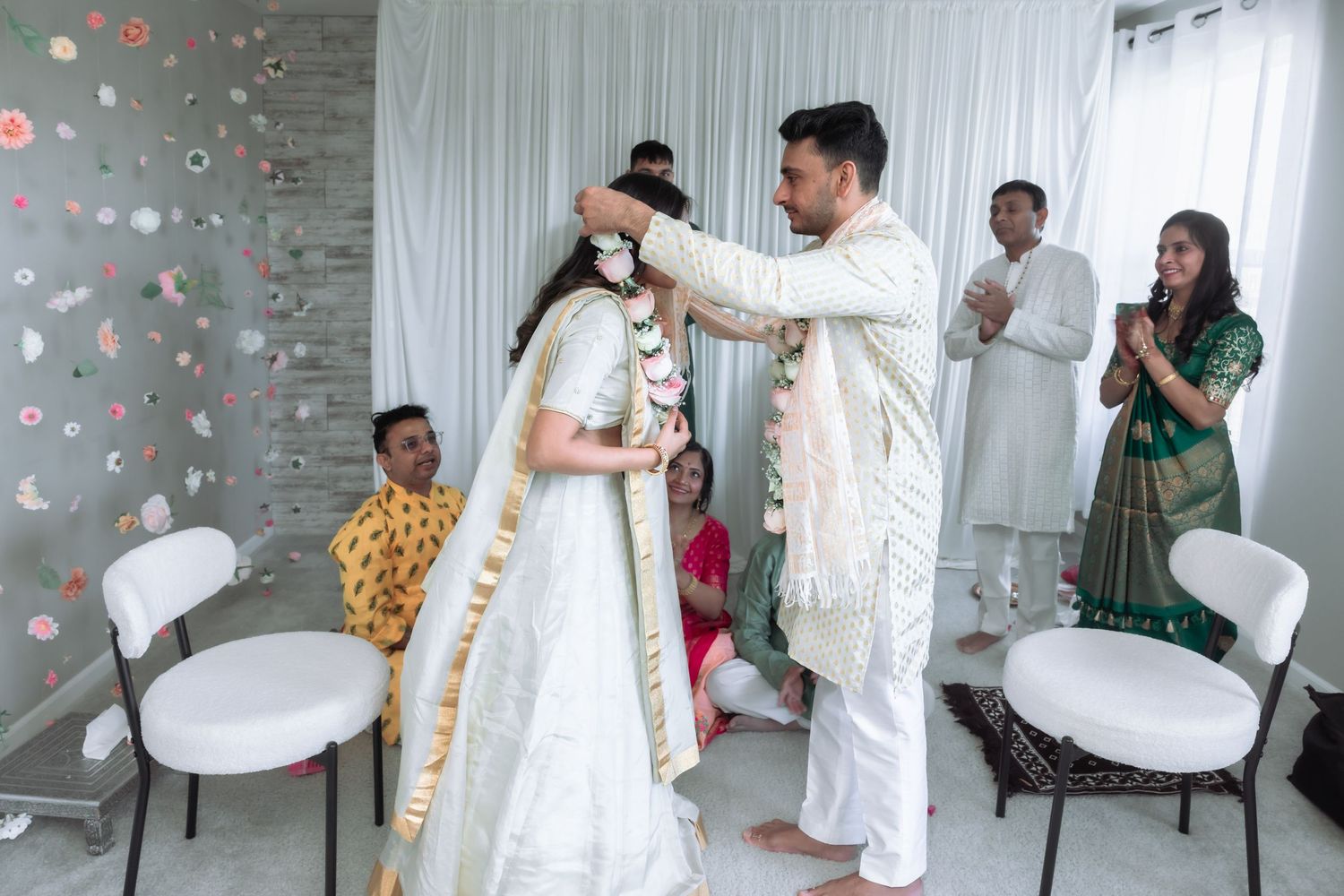Groom places a floral garland over the bride during a traditional Indian Varmala wedding ceremony.