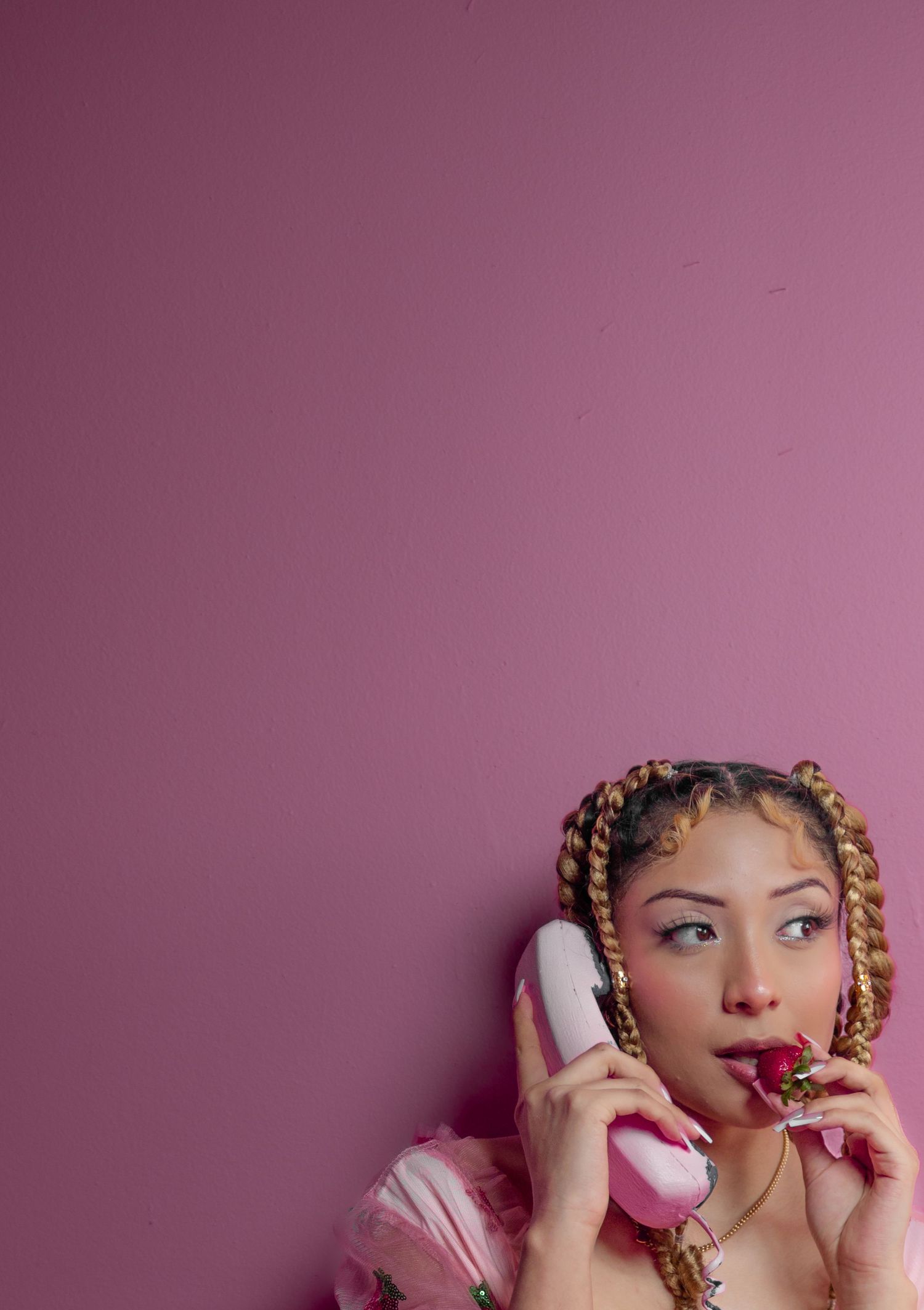 Woman with braided updo holds pink phone and rose against mauve background.