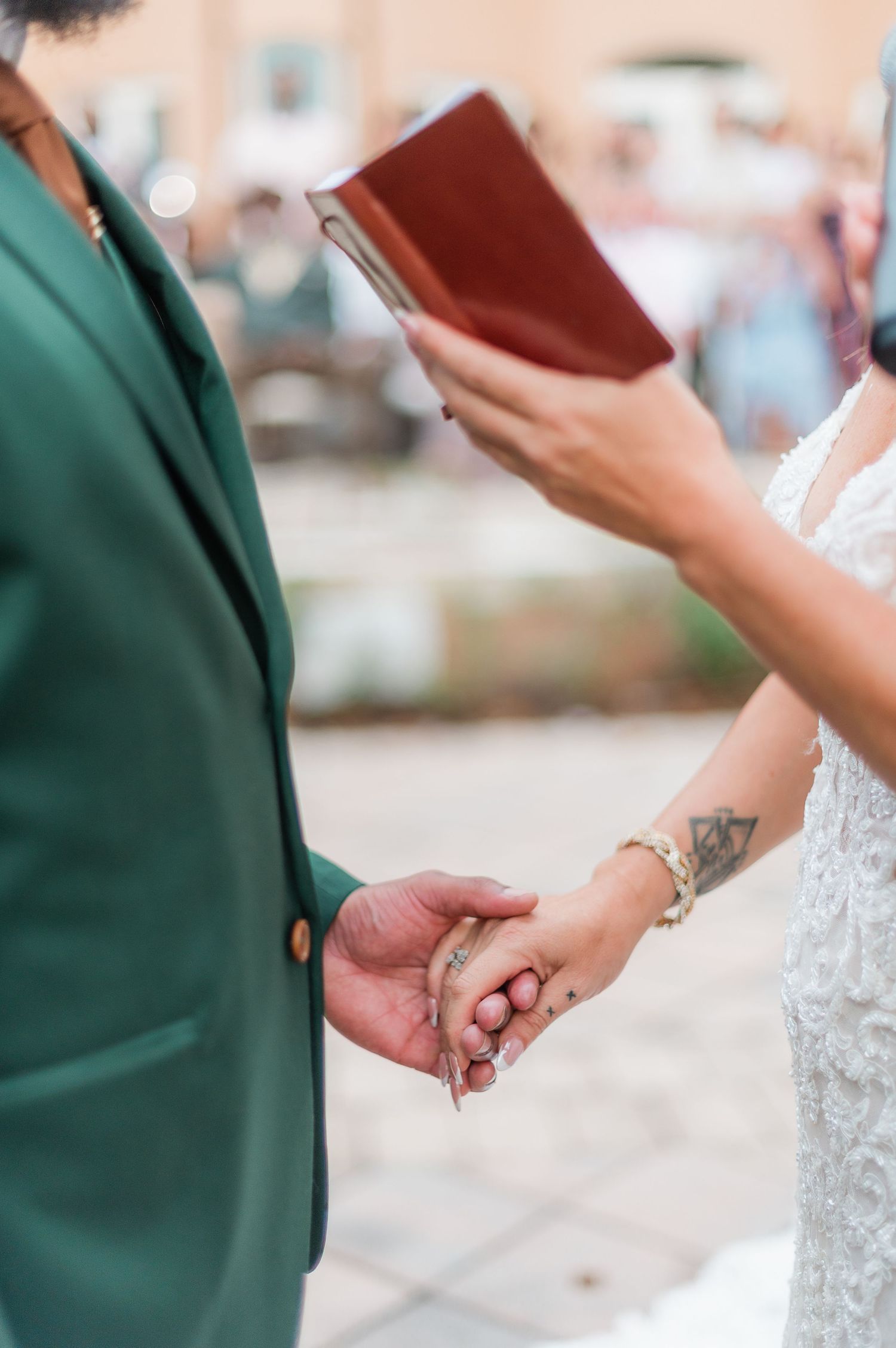 Close-up of wedding ceremony showing hands holding and officiant holding ceremony book.