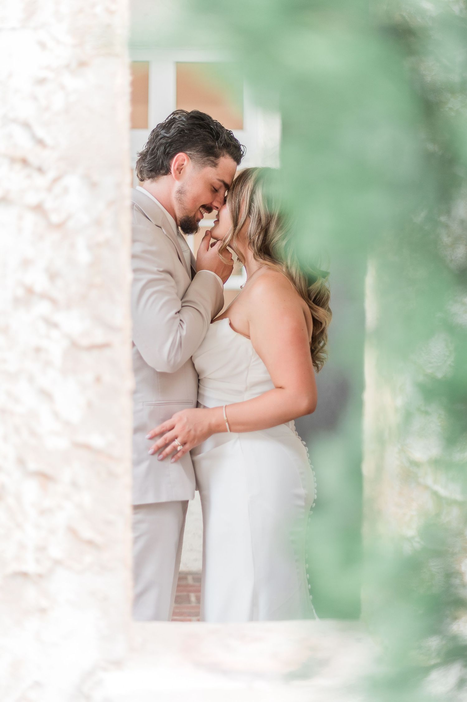 A romantic moment captured between newlyweds in a soft, dreamy garden setting with ethereal green bokeh effects.