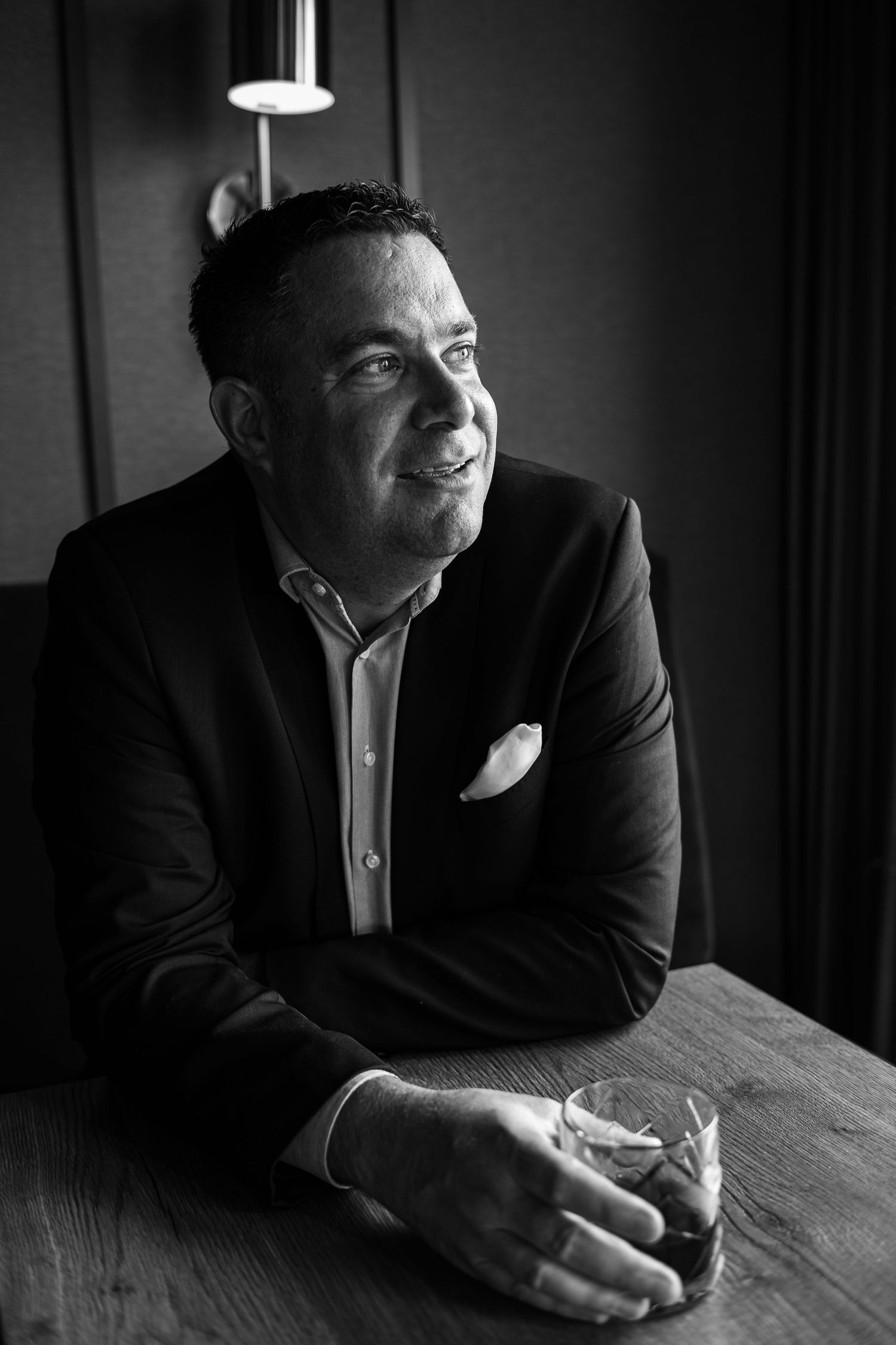 A series of black and white photographs showing someone in dark clothing leaning over a wooden table in dramatic lighting.