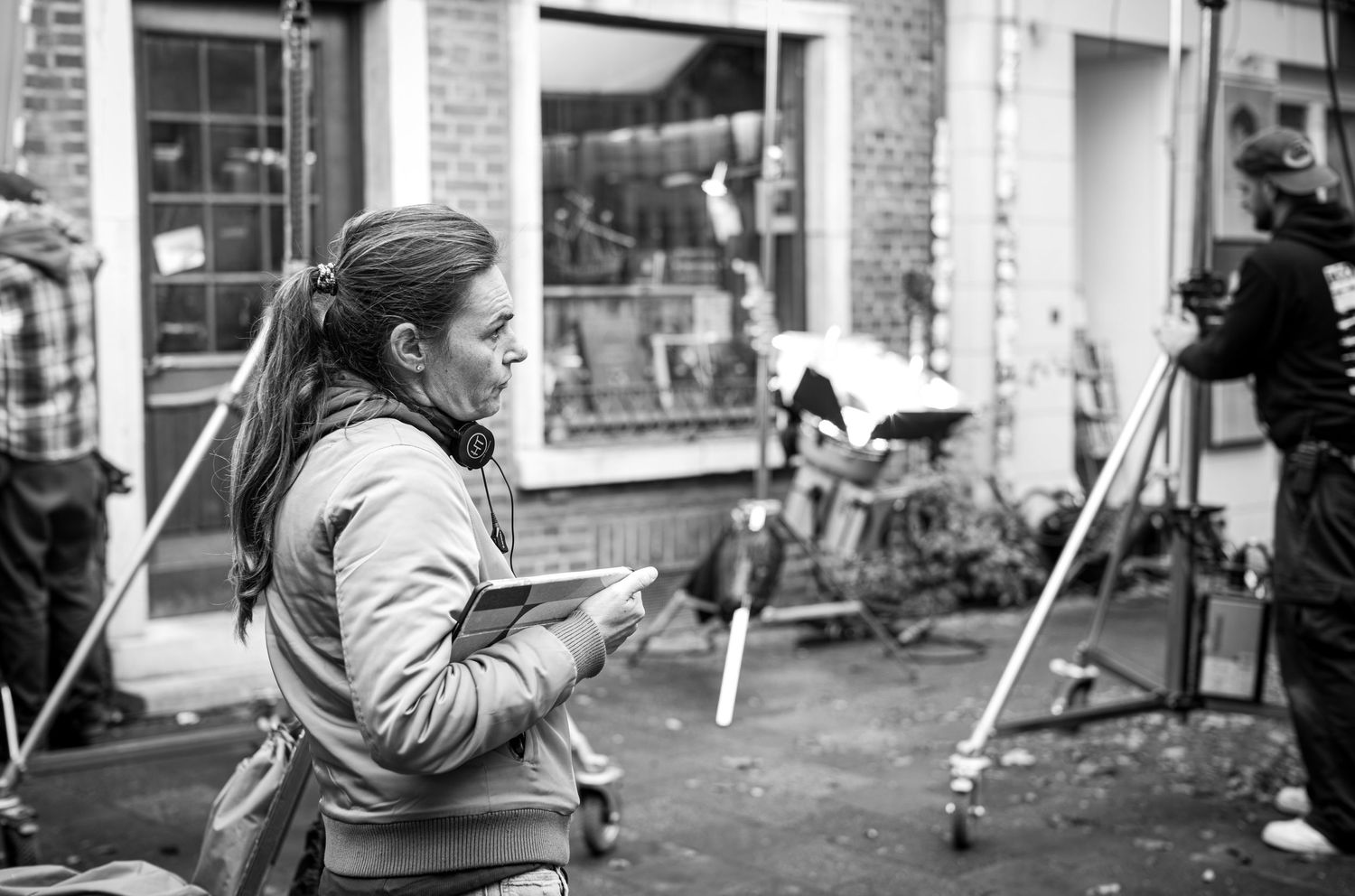 A sequence of black and white photos showing a person in winter clothing walking past brick storefronts.