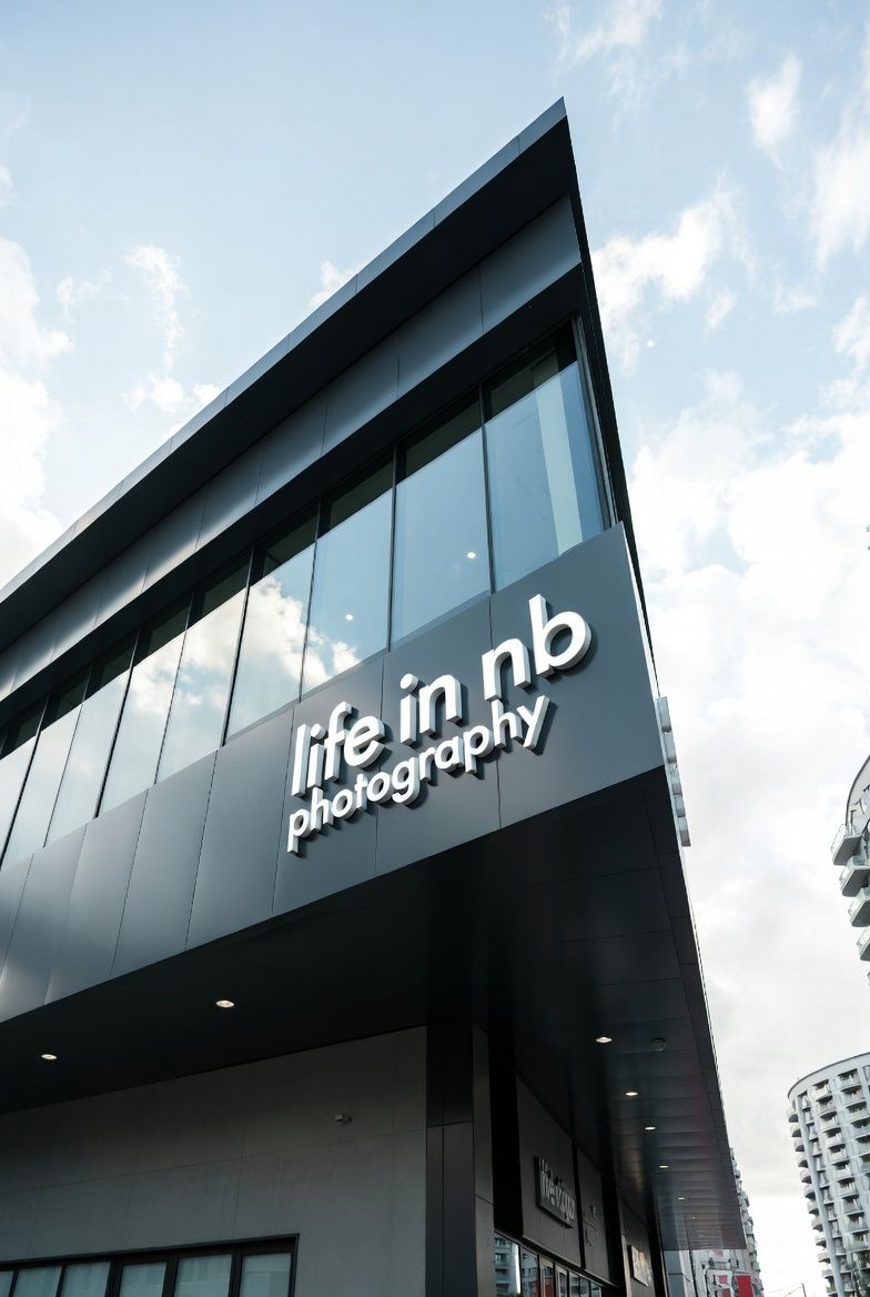 Modern black building exterior with 'life in nb photography' signage against blue sky.