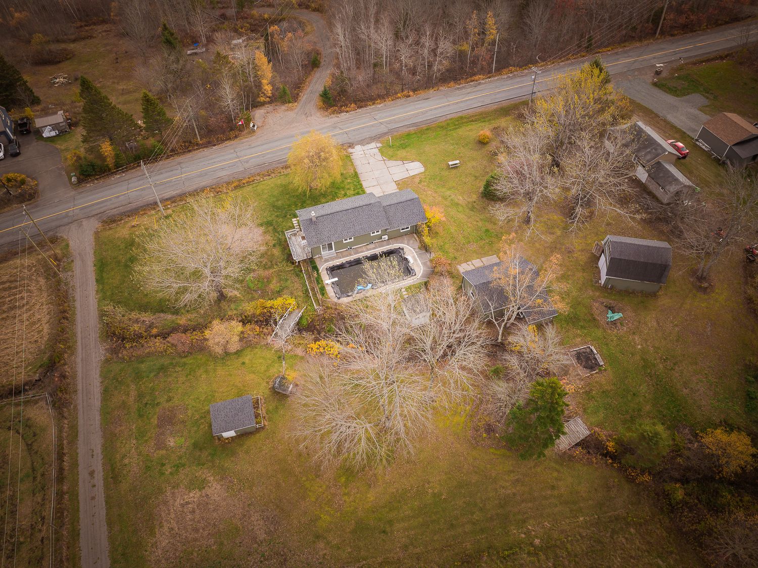 Aerial drone view of a rural residential property with autumn trees and winding roads in the countryside near Saint John.