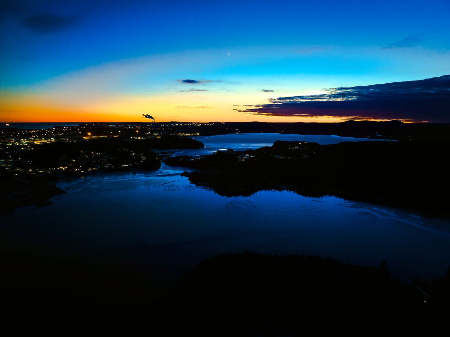 Dramatic sunset skyline over Saint John River with deep blue and orange colors, looking towards Dominion park in Saint John.