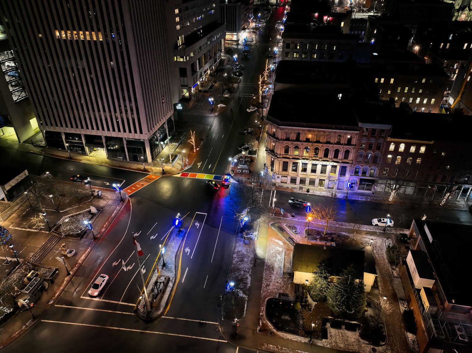 Aerial night view of city streets with colorful lights and modern buildings, bottom of King St in Saint John, NB.