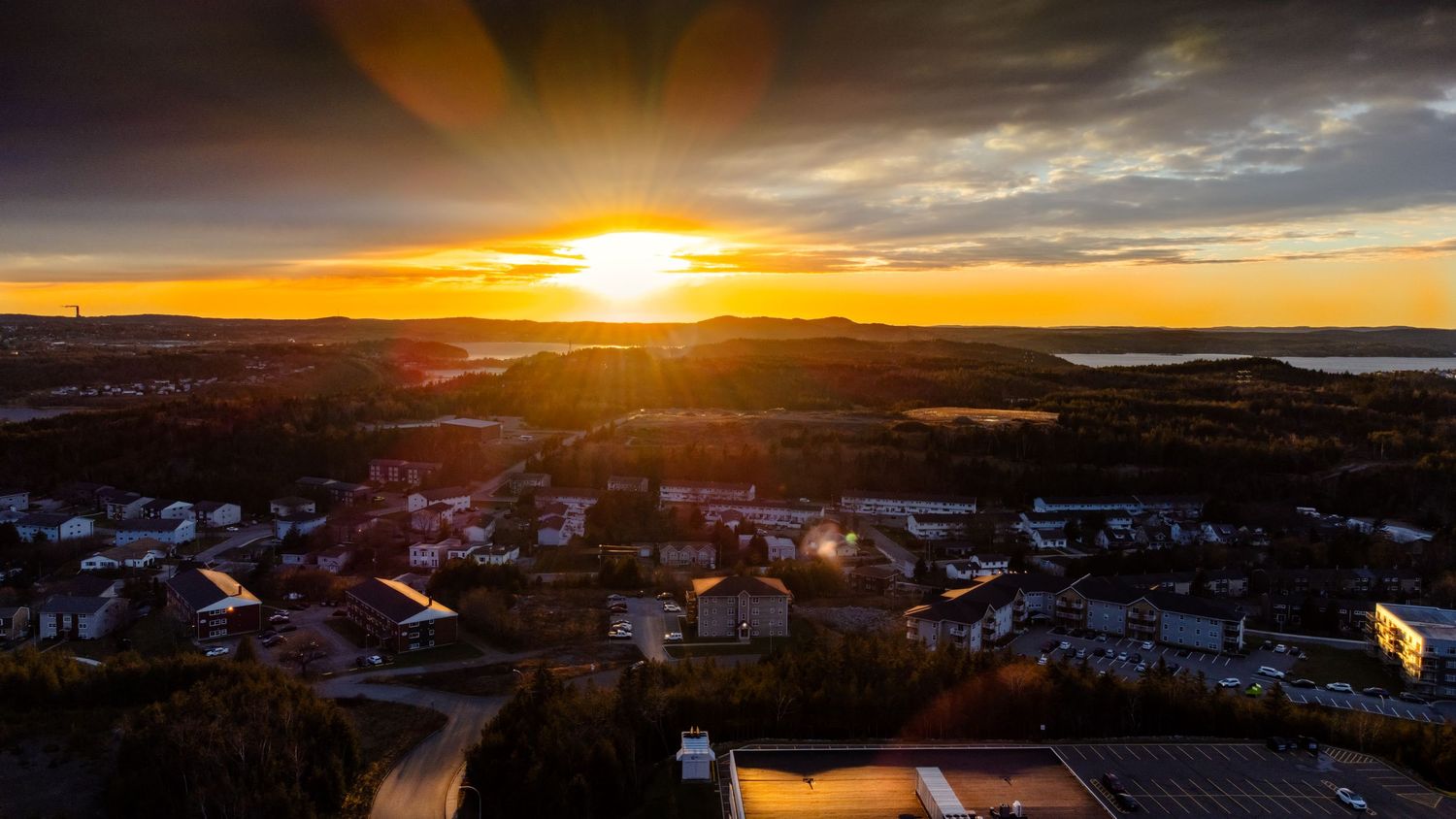 Dramatic sunset over north Saint John, looking towards the Saint John river, with golden light streaming through clouds.