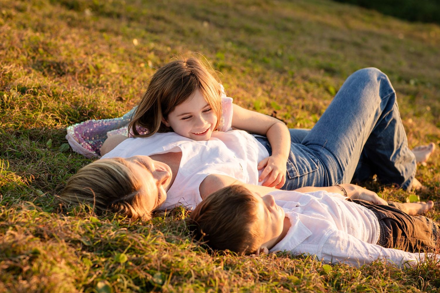 People lying together on grassy hill during sunset creating warm, candid moments.Family photography cabarita New South WalesCabarita headlan