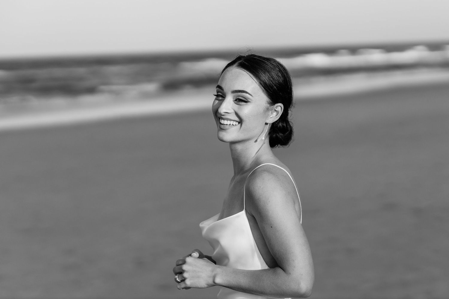 Black and white beach portraits of bride with ocean waves in background.