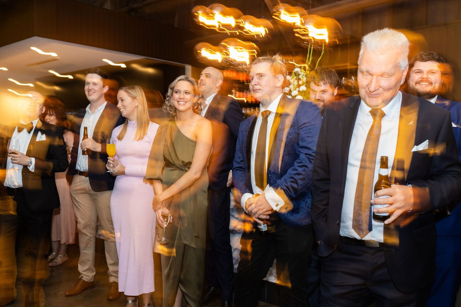 Wedding guests mingle and socialize during cocktail hour with ambient lighting.