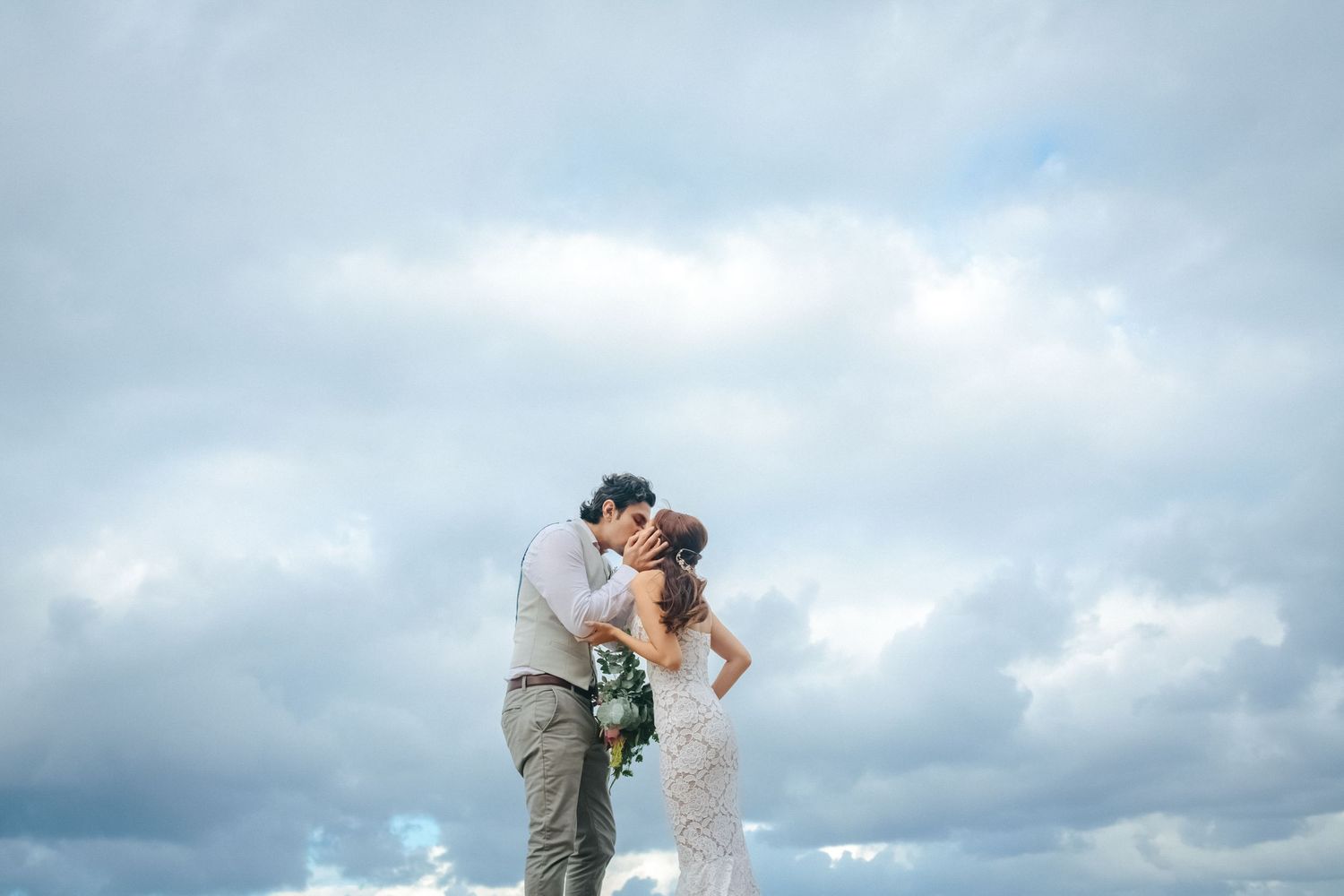 Wedding couple sharing intimate moment against dramatic cloudy sky.candid wedding photography Gold Coast
