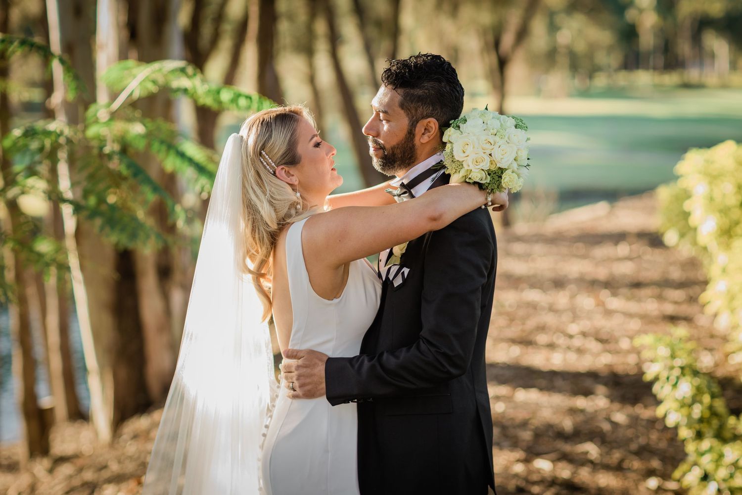 A couple shares romantic moments in an outdoor wooded setting during their wedding photoshoot. Surfers Paradise Golf Club wedding.