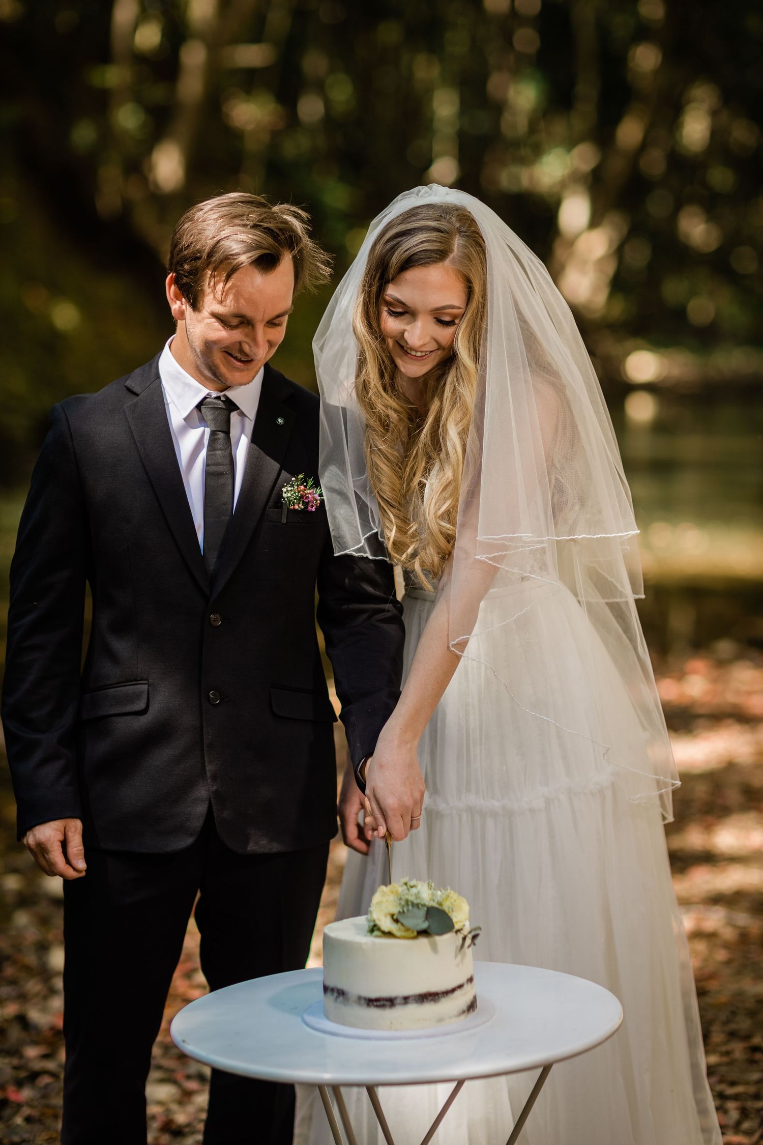 Couple sharing intimate moment next to wedding cake on outdoor table.Currumbin Valley wedding photography Gold Coast