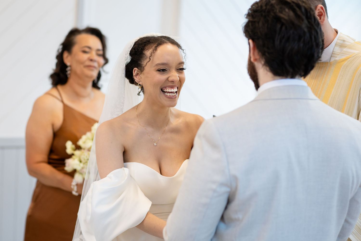 A romantic wedding ceremony moment captured in an elegant white chapel setting with soft natural lighting.