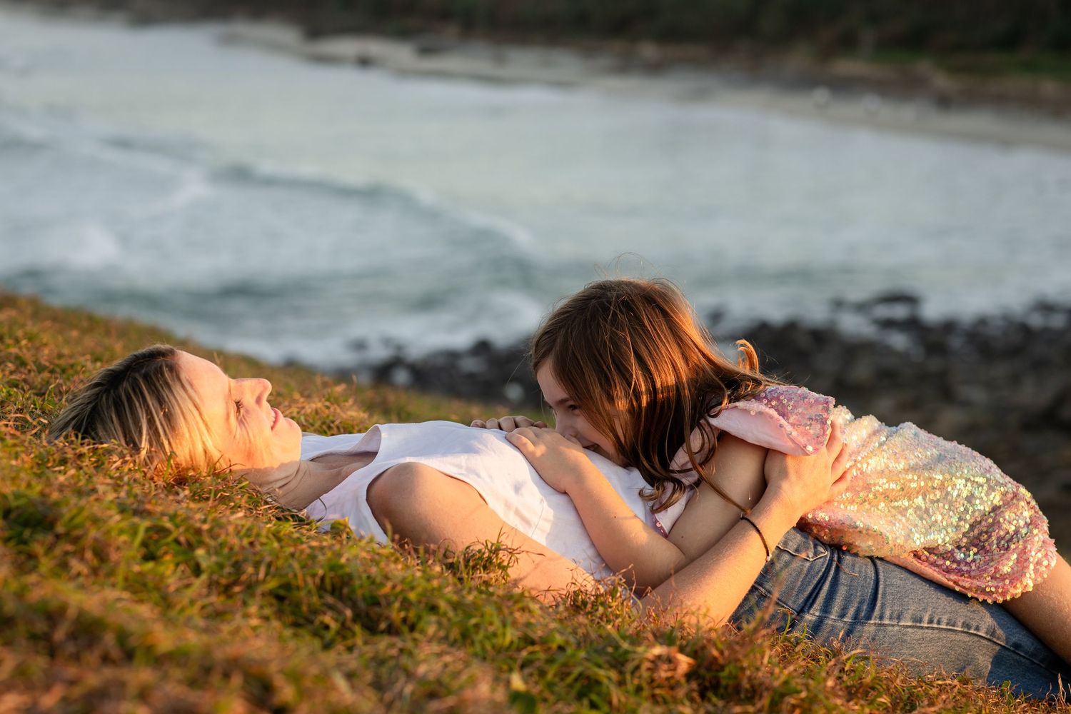 Group relaxing on coastal hillside during golden hour.Gold Coast candid family photographer. Cabarita headland