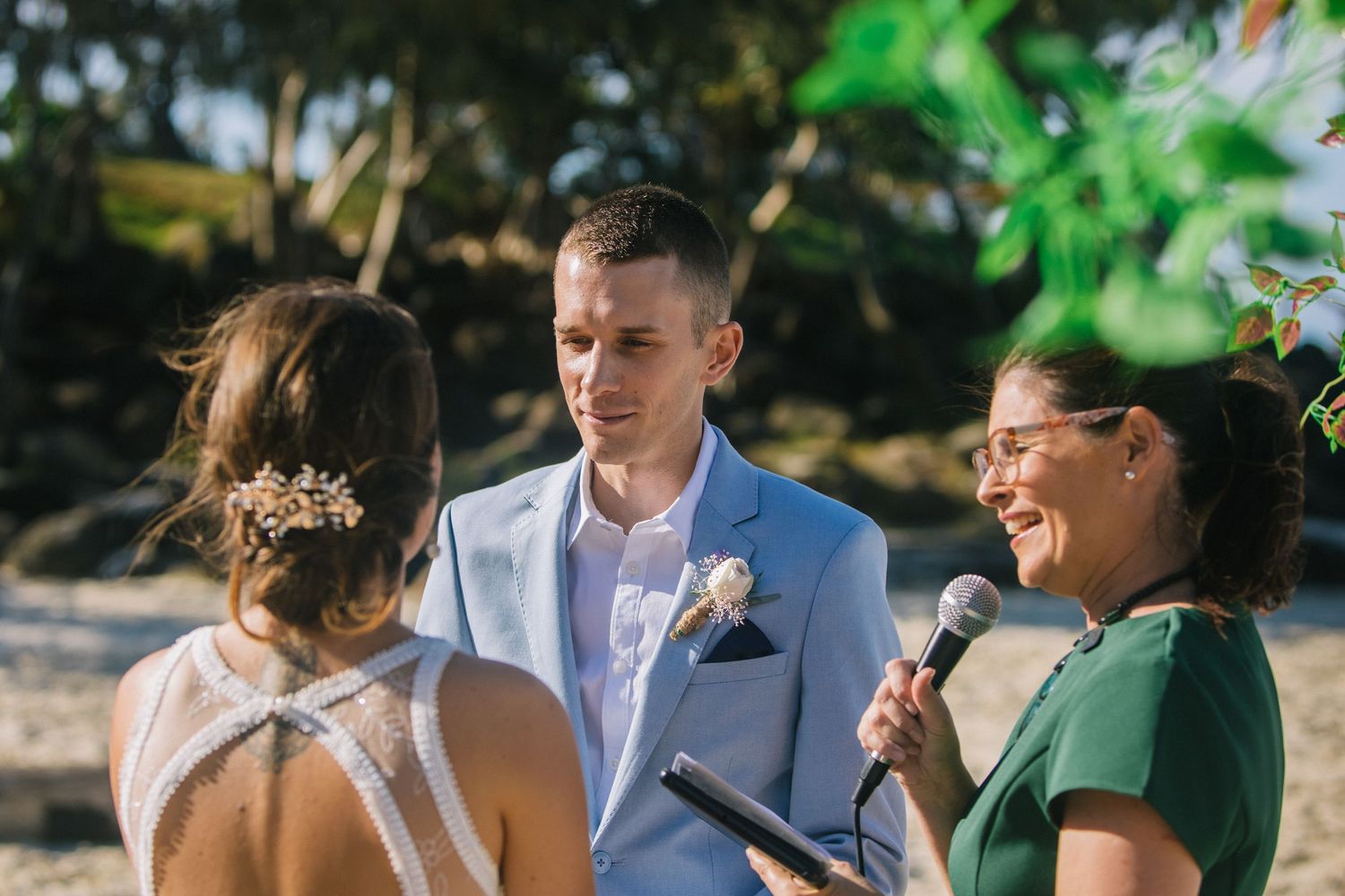 Intimate beach wedding ceremony with tropical greenery and ocean backdrop.