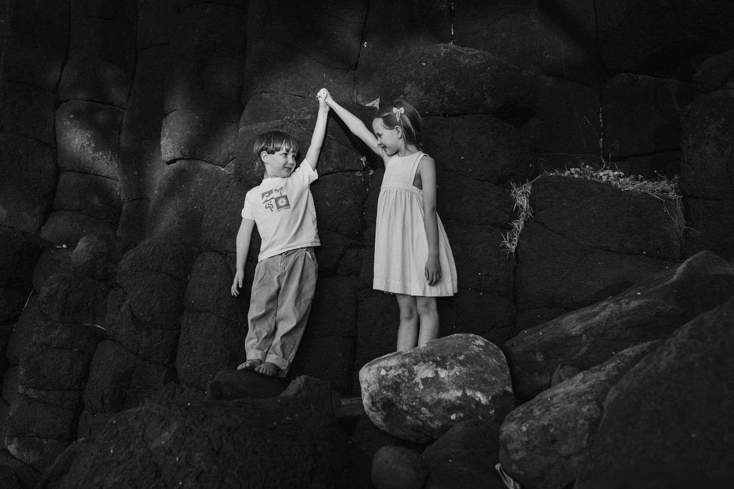 Silhouettes against a dark rocky backdrop in dramatic lighting.Fingal head family photos -  New South Wales Gold Coast candid family