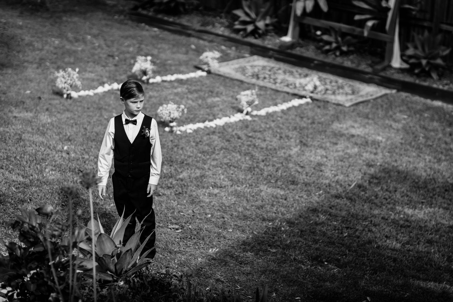 Outdoor wedding ceremony setup with white chairs arranged on a grassy lawn.