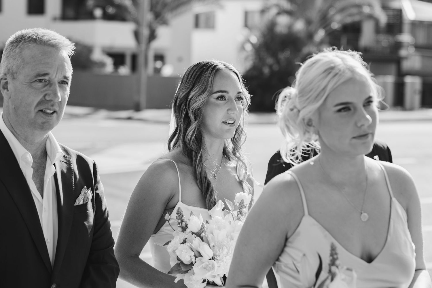 Wedding party members react emotionally during outdoor ceremony.