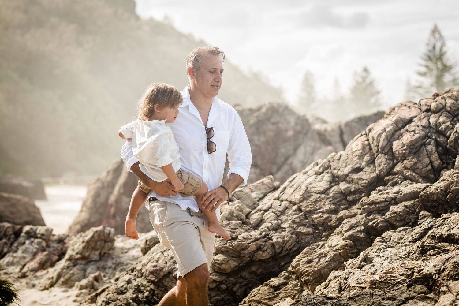 Family exploring rocky coastal formations during golden hour.Gold Coast candid family photographer.