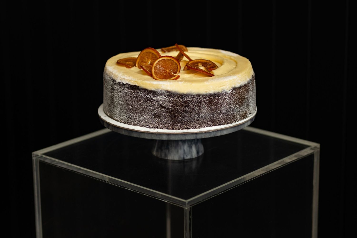 Elegant wedding cakes displayed on clear acrylic stands against dark background.