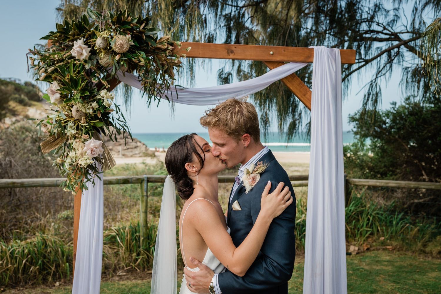 Outdoor wedding ceremony with white fabric arch and floral arrangements.Miami Burleigh heads beach wedding