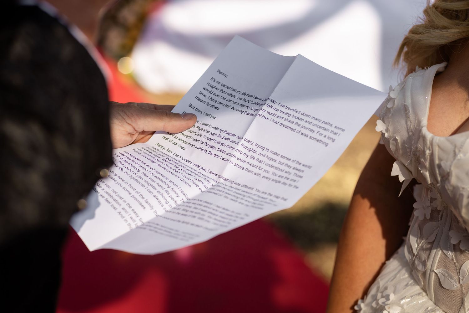Close-up of ceremony programs being held during outdoor wedding.