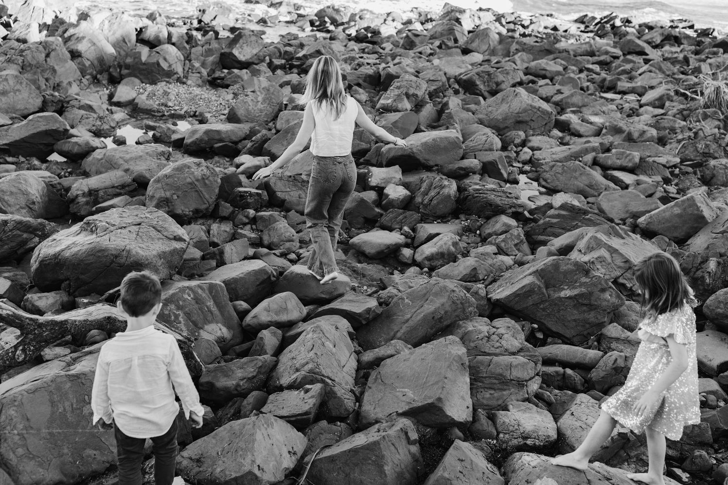 Group exploring rocky beach terrain during outdoor photoshoot.Gold Coast candid family photographer. Cabarita headland