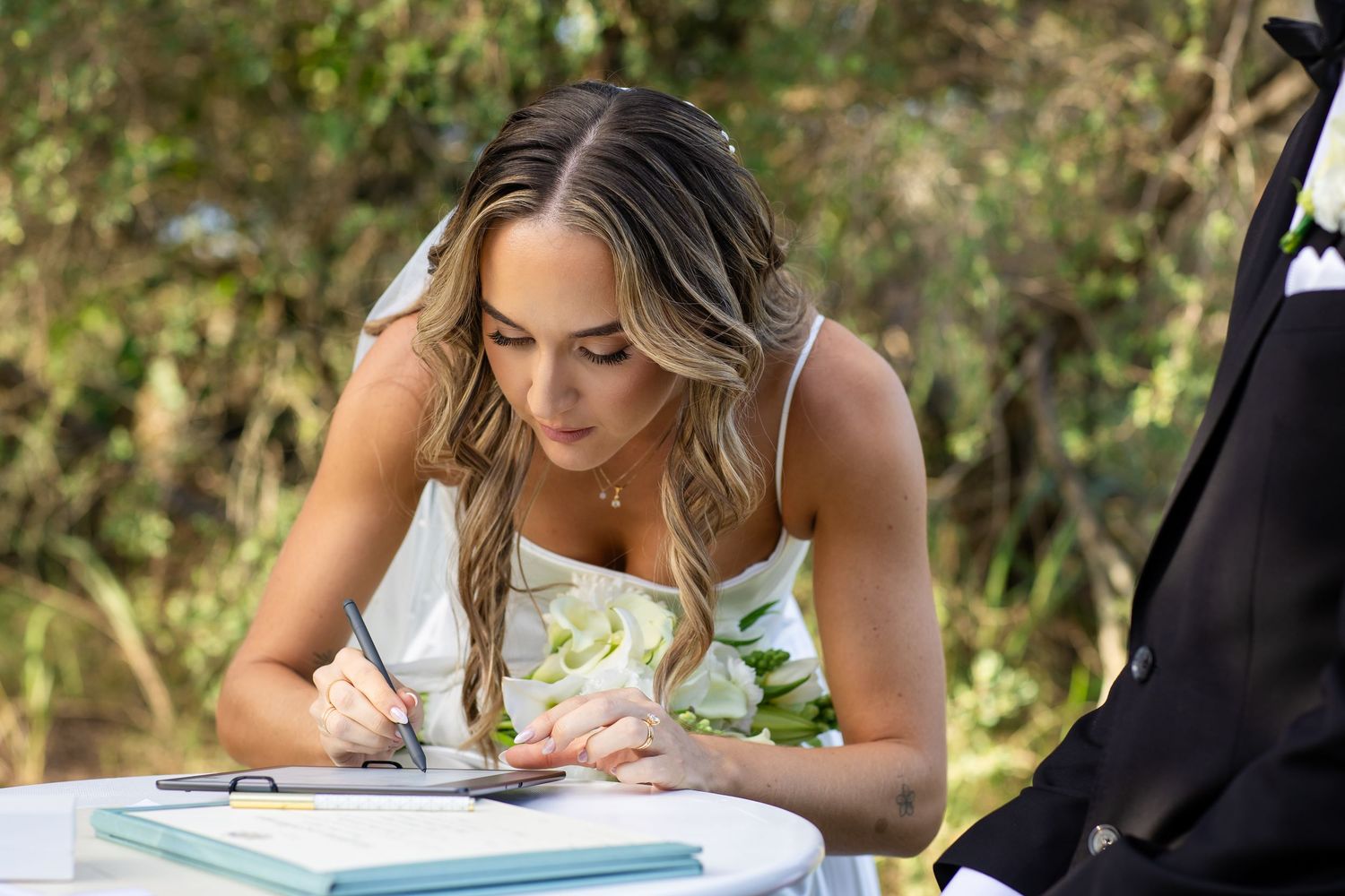 Wedding ceremony document signing outdoors with natural greenery background.beach wedding currumbin surf club wedding