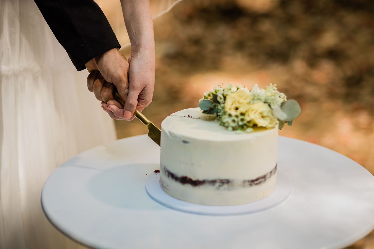 Wedding cake cutting sequence showing hands slicing into a white tiered cake with floral decorations.Currumbin Valley wedding photography Go