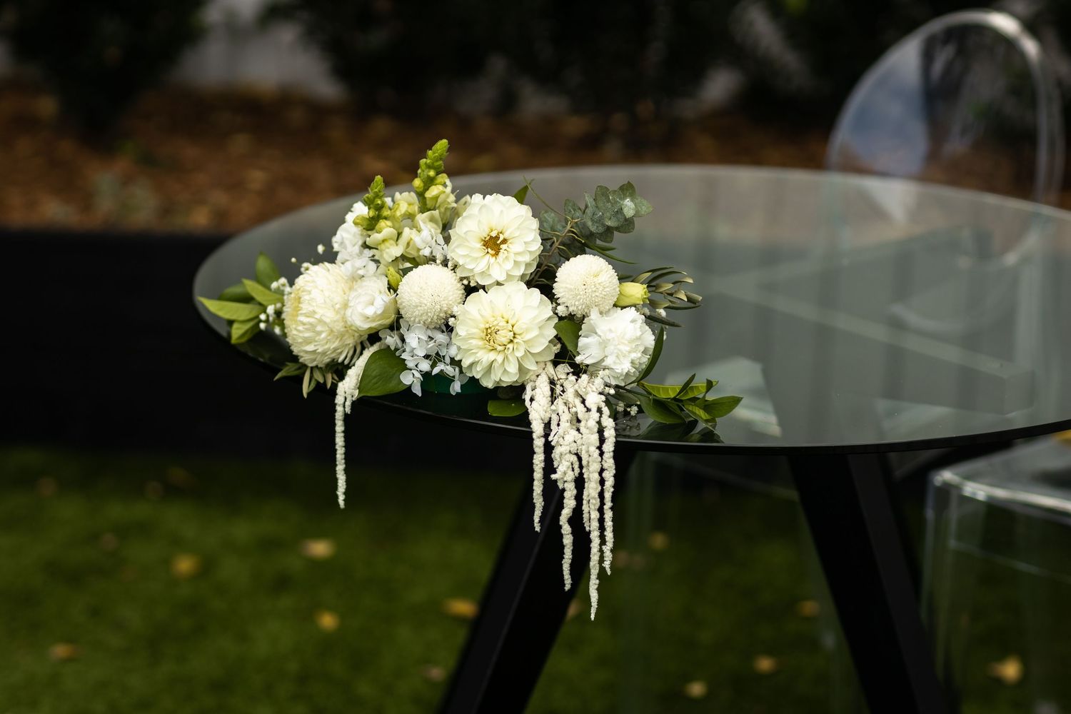 White floral arrangements with cascading elements on glass display stands.