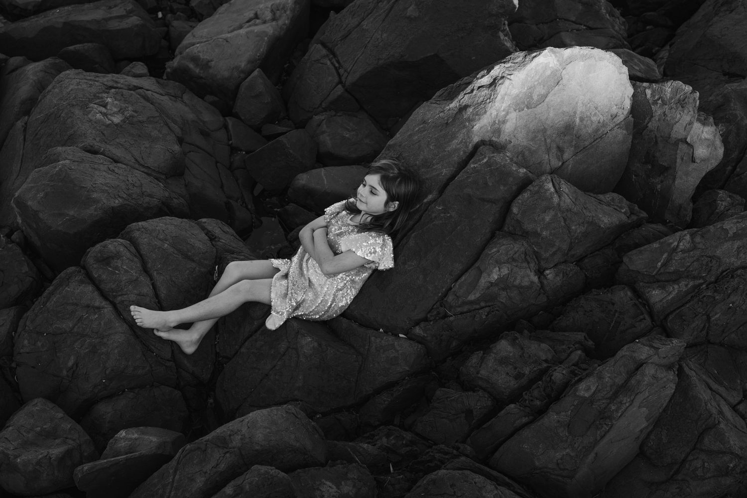 Dramatic black and white photo of people on rocky coastal formation. Gold Coast candid family photographer.
