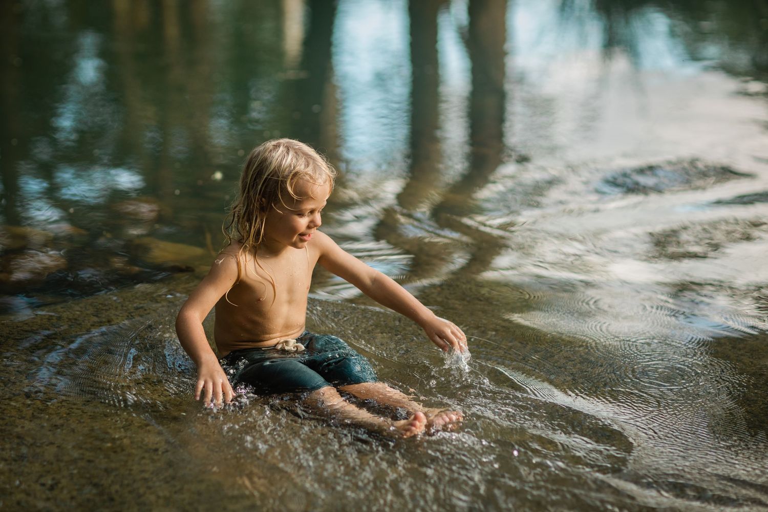 Kids splashing and playing in shallow creek water surrounded by trees.Gold Coast candid family photographer.