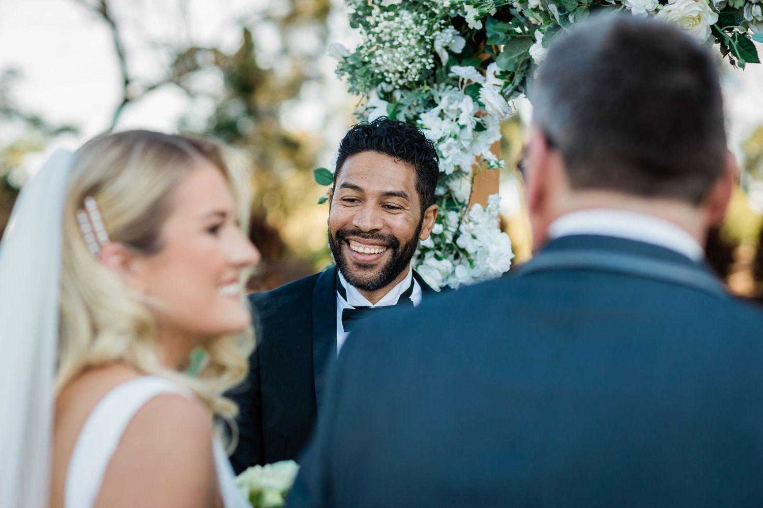 Intimate wedding ceremony moment captured under natural greenery outdoors.