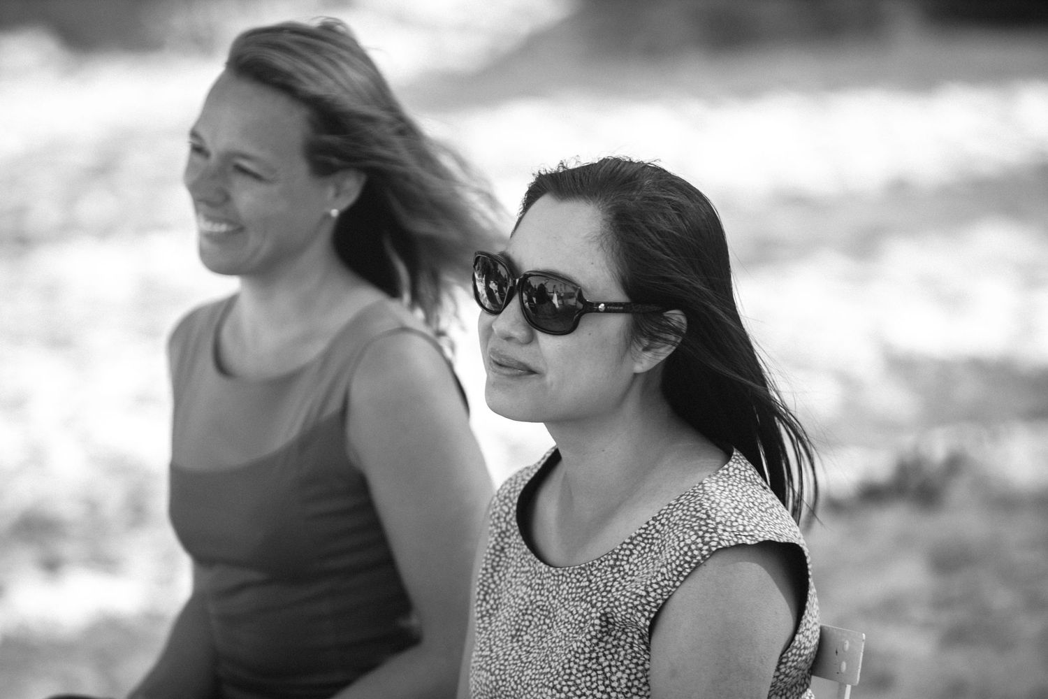 Black and white candid wedding moments showing guests enjoying a celebration on a sunny day.