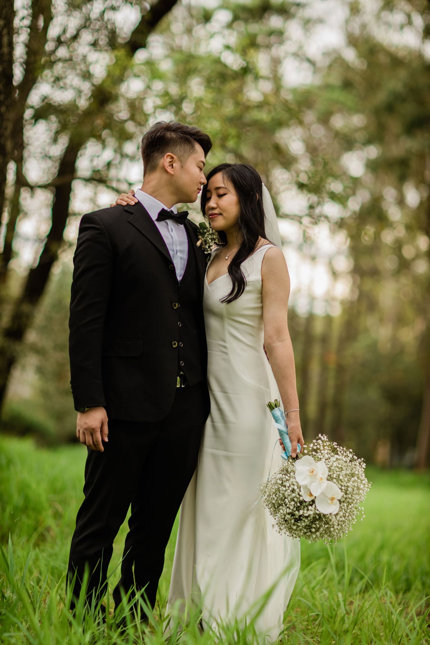 Wedding couple poses together in natural outdoor setting with delicate floral bouquet.candid wedding photography Gold Coast