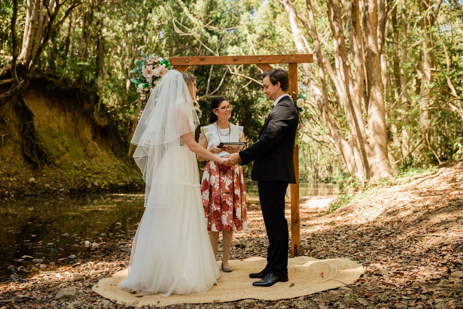 Intimate forest wedding ceremony with wooden arch and natural decor among tall trees.Currumbin Valley wedding photography Gold Coast